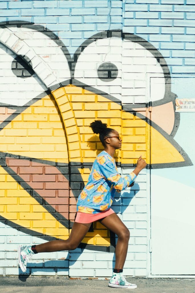 pexels-photo-1013328-1013328 Dynamic scene of a woman running against a colorful graffiti wall, capturing urban art energy.