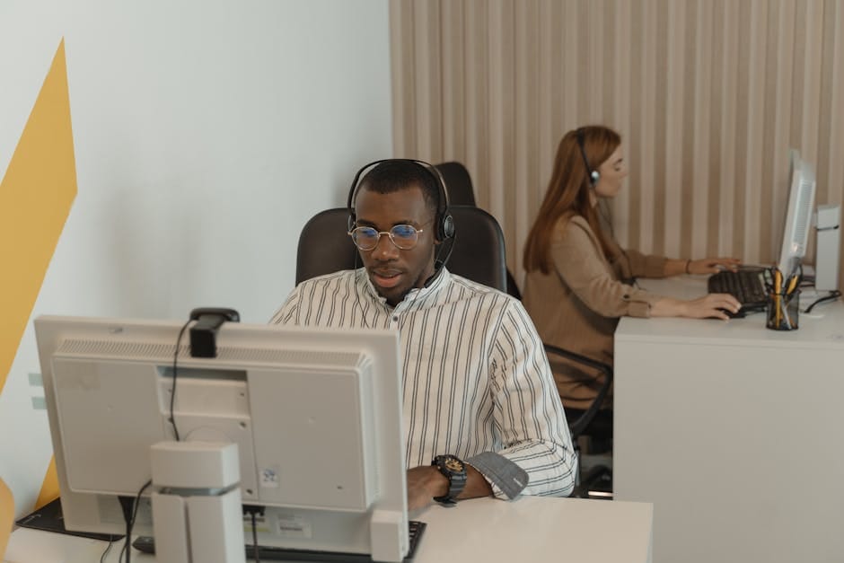 Two focused call center employees working with headsets and computers.